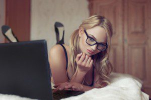 Sexy blonde woman in glasses typing on laptop at home